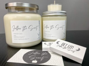 Set of candles in glass jars with "Follow the Scent" labels. A matchbox that says "get lit" laid in the front